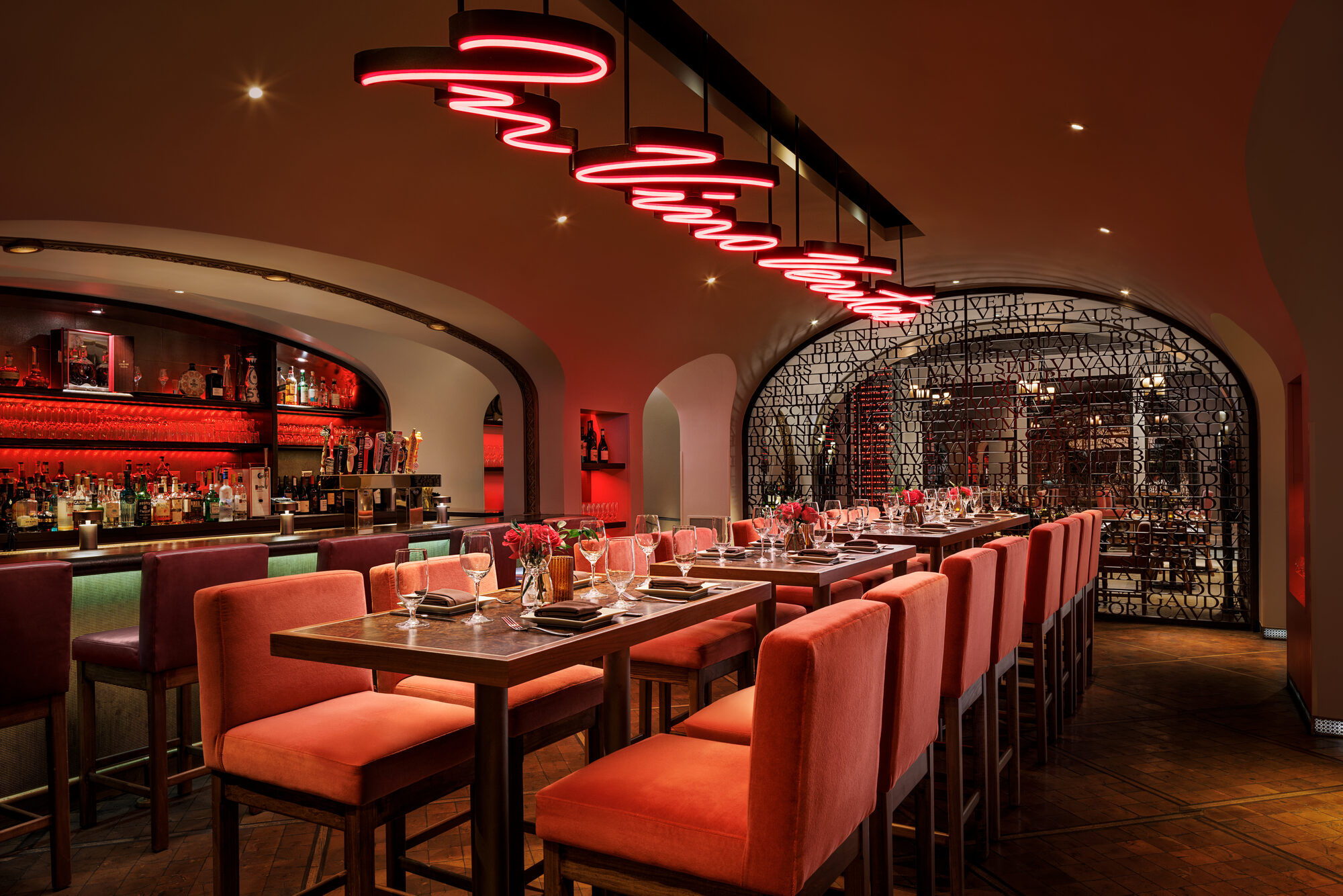 La Cave's intimate wine cellar wrapped in bottle-lined walls under warm red neon